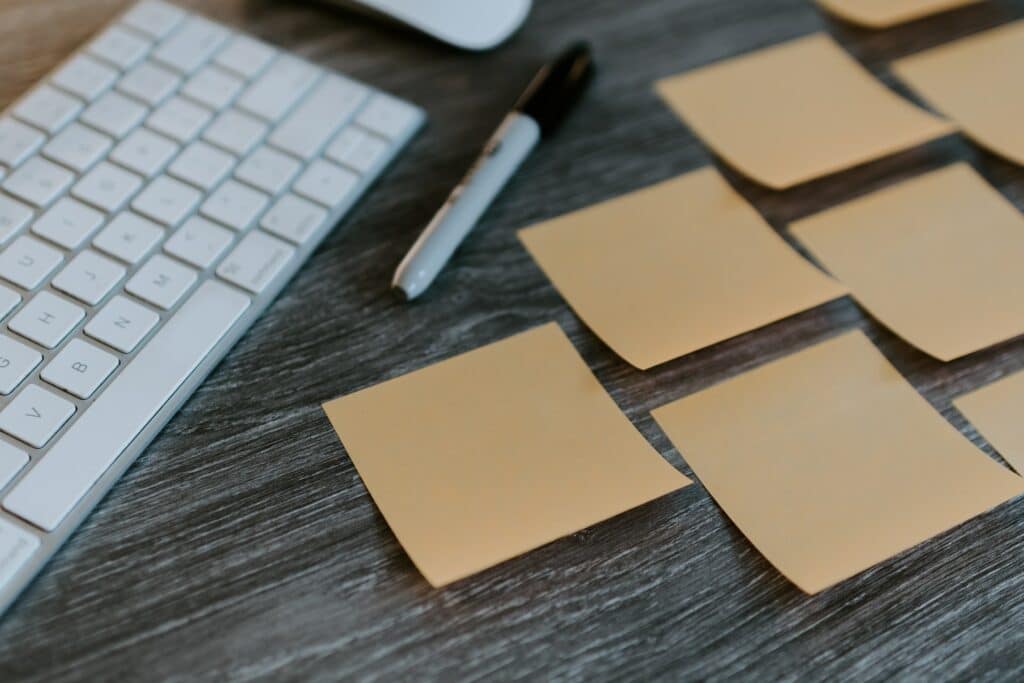 Post-it notes and a sharpie next to a keyboard on a desk as someone learns how to write video tutorials
  