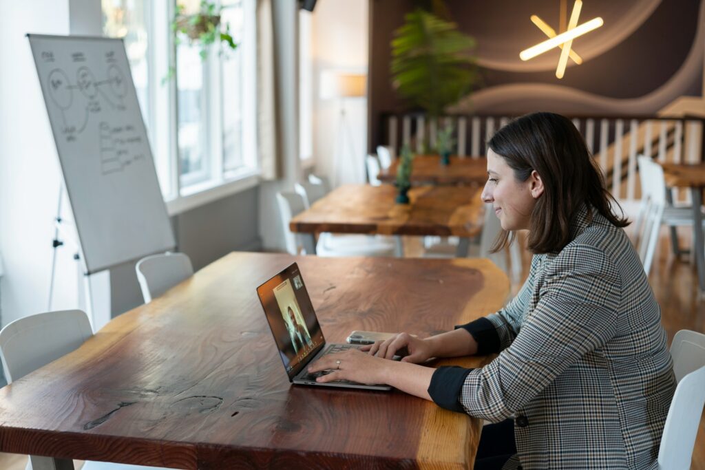 A person sat in a large office area on a zoom call with a whiteboard in the background behind the large desk they are sat at looking to have better online meetings.