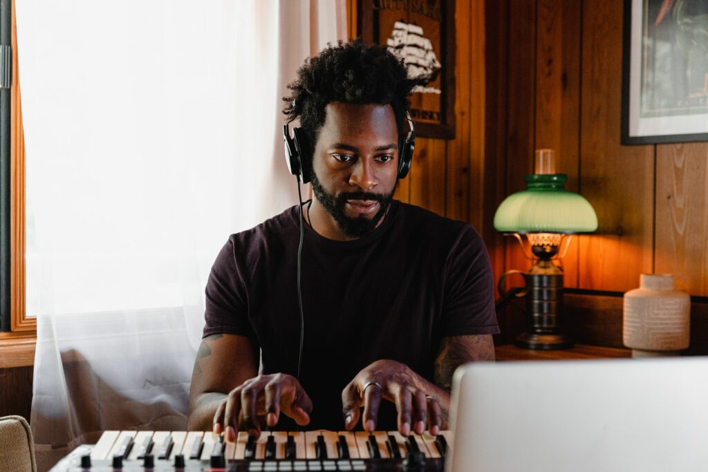 A person at a laptop playing a keyboard who will live stream this music